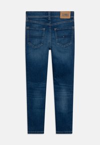 Tummansinisen denimin kapeat farkut, joissa on sileä pinta, viisi taskua ja nahkainen merkki vyötäröllä.