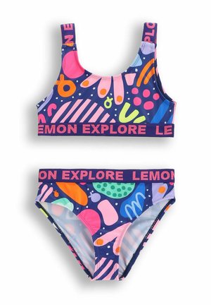 Dwuczęściowy strój kąpielowy z granatowym tłem i wielobarwnymi, abstrakcyjnymi wzorami. Góra ma grube ramiączka i wspierający pas.