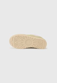 Sneakerzool met een textuur van rubber aan de onderkant in beige, met een stervormig patroon, en een lichtgroene bovenkant met mesh-details.