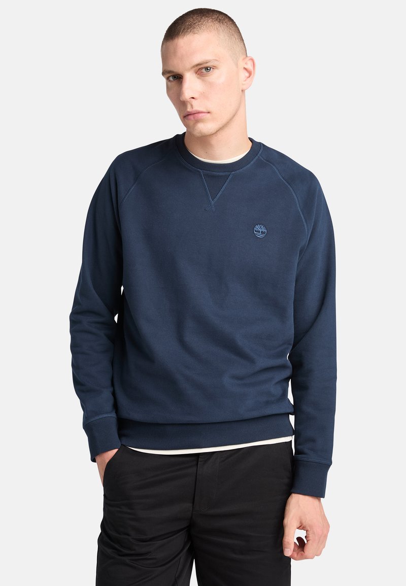 Sudadera de color azul marino hecha de una mezcla de algodón. Cuenta con un cuello redondo acanalado, mangas largas y un pequeño logo en el pecho. Textura suave.