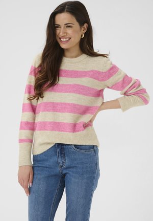 Hellbeiger Pullover mit kräftigen pinkfarbenen Streifen, Rundhalsausschnitt, gerippten Bündchen und Saum, aus weichem Material gefertigt. Getragen mit blauen Jeans.