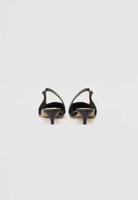 Black leather heeled shoes with a pointed toe, open back, and a low, narrow heel. Smooth texture with minimal detailing.
