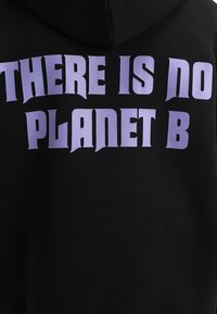 Sudadera negra con texto morado en negrita en la parte trasera que dice "NO HAY UN PLANETA B" en letras mayúsculas.