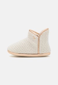 Light beige boot slippers with a textured knit upper, rose gold accents, and soft sole. Ankle-height design with a rounded toe.