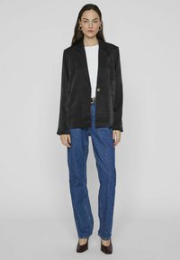 Juodas švarkas su vienu mygtuku, ilgomis rankovėmis, derinamas su baltu marškinėliu ir mėlynomis tiesiomis džinsomis. Lygus paviršius ir pritaikytas dizainas.