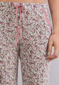 Loungebroek met bloemenprint, voorzien van een witte achtergrond met roze en groene rozen, elastische tailleband, warme zakken en een verstelbaar koord.