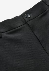 Pantaloni neri con un motivo a righe verticali testurizzato. Presentano una patta frontale e un dettaglio con bottone nero vicino alla vita.
