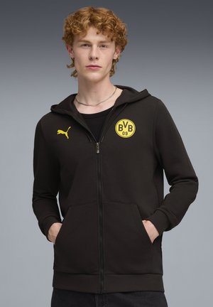 Sort zip-up hættejakke lavet af blødt stof, har en kængurulomme, ribbede manchetter og et gult rundt logo med "BVB 09" på brystet.