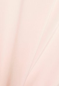 Tissu rose clair avec une texture lisse et soyeuse, présentant un drapé doux et un éclat subtil, idéal pour les vêtements ou accessoires.