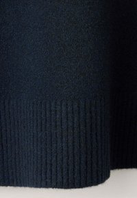 Tissu tricoté bleu marine foncé avec un motif côtelé au bas, probablement une partie d’un pull ou d’un vêtement.