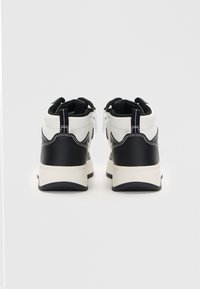 Αθλητικά παπούτσια με ψηλή γαρεία, που διαθέτουν μαύρη δερμάτινη βάση και λευκή συνθετική επάνω επιφάνεια. Μαύρες λεπτομέρειες και αντίθετη ραφή. Μεταλλικό φερμουάρ στο πίσω μέρος.