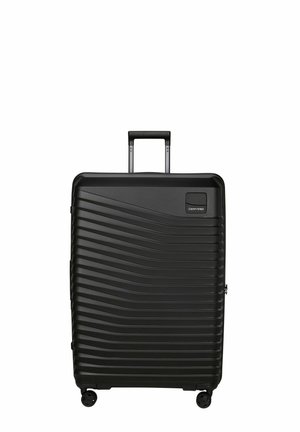 Valise rigide noire à motif ondulé horizontal, équipée de quatre roues et d'une poignée extensible, marque Samsonite.