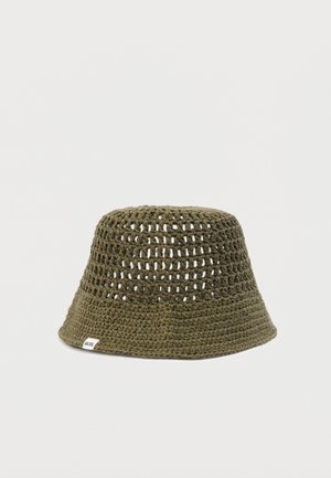 Chapeau bob en crochet vert olive avec un motif à mailles ouvertes et une petite étiquette en tissu blanc sur le bord.