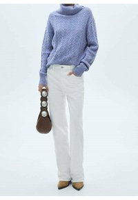 Suéter de cuello alto de punto con cable en color púrpura claro, vaqueros acampanados blancos, bolso marrón con detalles metálicos y zapatos de punta.