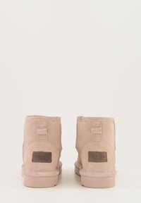 Lichtbeige nubuck enkellaarzen met ronde neus, platte zool, zijstiksels en een tan logo-label op de achterkant.