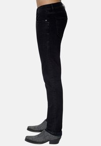Jeans de mezclilla negra con un corte ajustado, que cuentan con cinco bolsillos y costuras sutiles. Acompañados de botas tobilleras grises con punta afilada.