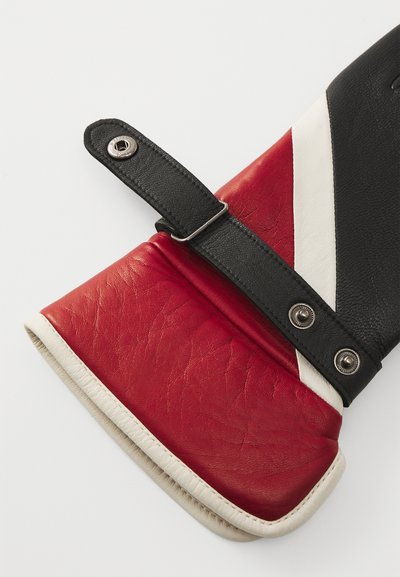 Gant en cuir avec des sections rouges, noires et blanches. Présente une finition texturée, une sangle avec une fermeture à pression et un intérieur doux en blanc.