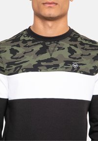 Sweatshirt met lange mouwen, met een bovenstuk in camouflagepatroon in groen en zwart, een witte horizontale streep en een zwart onderste deel.