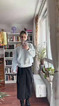 Hele sinine üler suurusega kapuutsiga sviiter, millel on soonikkoes mansetid, koos mustade cargo-pükstega, millel on küljetaskud ja nööriga hemid, kandmiseks mustade saapadega.