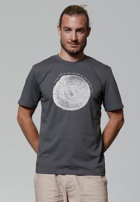 Grijze katoenen t-shirt met een cirkelvormige houtnerfafbeelding met daaromheen tekst. Korte mouwen, ronde hals en een normale pasvorm.