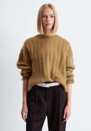 Brauner Mohair-Pullover mit rundem Ausschnitt, lockerer Passform und gerippten Bündchen, kombiniert mit dunklen Hosen und einem weißen Gürtel. Schlichtes Design.