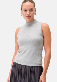 Top grigio senza maniche con colletto alto realizzato in morbido tessuto a maglia, abbinato a una gonna scura plissettata. Design semplice con una silhouette aderente.