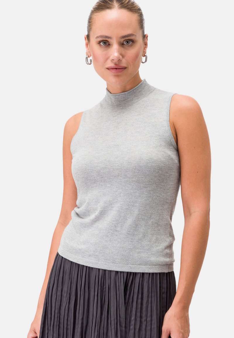 Top grigio senza maniche con colletto alto realizzato in morbido tessuto a maglia, abbinato a una gonna scura plissettata. Design semplice con una silhouette aderente.