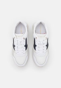 Zapatillas deportivas blancas con acentos en azul marino y beige, que cuentan con una parte superior de cuero suave, punta redonda y un diseño clásico de cordones.