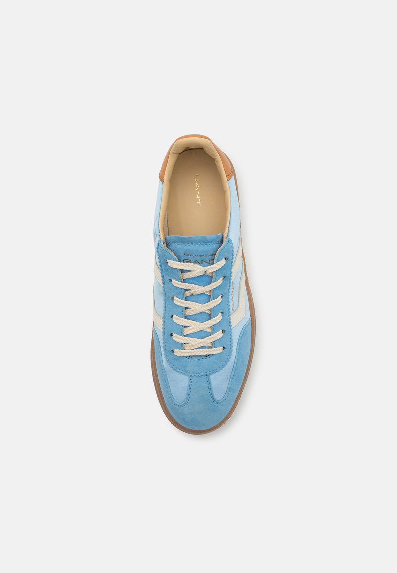 Niebieskie zamszowe sneakersy z brązowymi akcentami i białymi detalami. Posiadają zaokrąglony czubek, beżowe sznurowadła oraz teksturowaną gumową podeszwę. Widoczne logo marki.