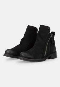 Botines de ante negro con un acabado ligeramente desgastado y una cremallera lateral. Presentan un tacón bajo y una puntera redondeada para mayor comodidad.
