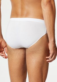 Witte katoenen slip met een gladde textuur, elastische tailleband en minimalistisch ontwerp, met een aansluitende snit en een lage achterkant.