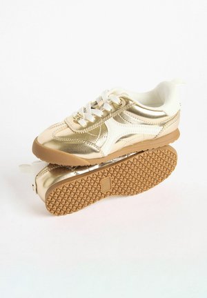 Goldene metallische Sneaker mit weißen Akzenten, Schnürdesign, gepolstertem Zungenbereich und strukturiertem Gummisohle. Verfügt über ein glattes Obermaterial und ein Logo-Detail.