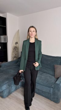 Roheline bleiser musta särke peal, sobitatud mustade pükstega. Komplekti täiendab must käekott ning taustal on tekstuuriga sinine diivan.