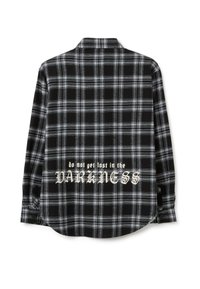 Zwart-wit geruite flanellen shirt met lange mouwen en een gebogen zoom. Bevat de tekst "raak niet verloren in de DONKERTE" op de achterkant.