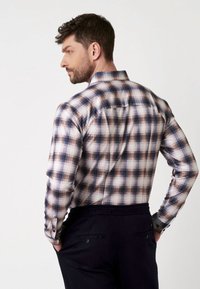 Heren long-sleeve geruit overhemd in wit, blauw en bruin tinten. Beschikt over een klassieke kraag en knopenmanchetten, met een relaxte pasvorm en een gestructureerde stof.