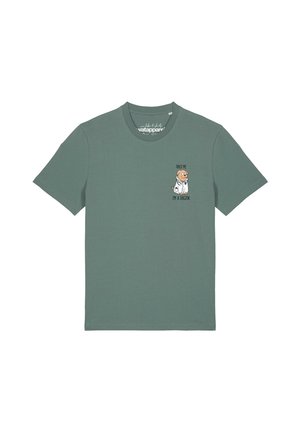 Grünes T-Shirt mit kurzen Ärmeln mit einem kleinen Cartoon-Hund, der einen weißen Laborkittel trägt, und dem Text "Trust me I'm a dogtor" auf der Brust.