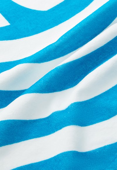 Turquoise and white striped beach towel featuring soft, textured fabric with alternating bold stripes, creating a vibrant wavy pattern.
