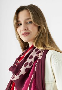 Kleurrijke sjaal met een mix van stippen en effen patronen in bordeaux, roze en rode tinten, gemaakt van zachte stof met een vloeiende design.