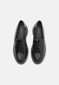 Sorte patenterte skinnloafer med en glatt finish, som har en sydd søm og kontrasterende teksturerte detaljer på en gummisåle.