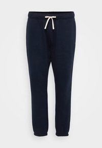 Granatowe spodnie dresowe z elastycznym pasem, regulowanym sznurkiem i ściągaczami na kostkach. Wykonane z miękkiej, teksturowanej tkaniny bawełnianej.