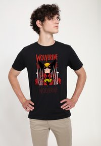 Černé bavlněné tričko s barevným grafickým motivem Wolverina s drápy a textem "Wolverine" tučným červeným písmem, umístěným na jednobarevném pozadí.