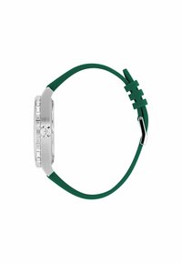 Montre-bracelet avec un boîtier transparent, un bracelet en silicone vert, des accents en acier inoxydable et un cadran rectangulaire. Éléments de design simples et modernes.