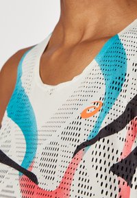 Sporttopp med en blandning av ljusa färger, mesh-textur och ett flerfärgat abstrakt mönster med orange logodetalj.