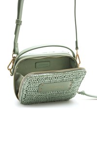 Bolso bandolera verde con textura tejida y detalles de cuero liso, herrajes dorados y cierre de cremallera. El interior está forrado y es espacioso.