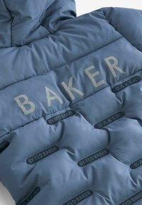 Pūkinė striukė prislopinto mėlyno audinio, su siuvinėta tekstūra, išsemtu „BAKER“ logotipu ir juodais „BY TED BAKER“ prekės ženklo akcentais.