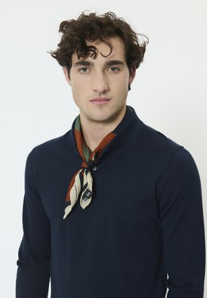 Navy blue knit polo shirt with a two-button collar and a patterned scarf in shades of brown, green, and cream tied around the neck.