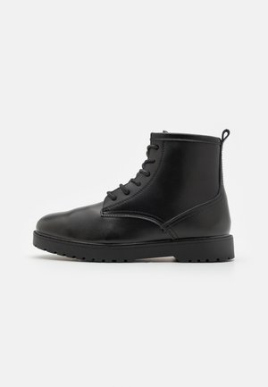 Stivale ankle in pelle nera con punta rotonda, design con lacci, suola texturizzata e una piccola linguetta sul retro per facilitare l'indossamento.