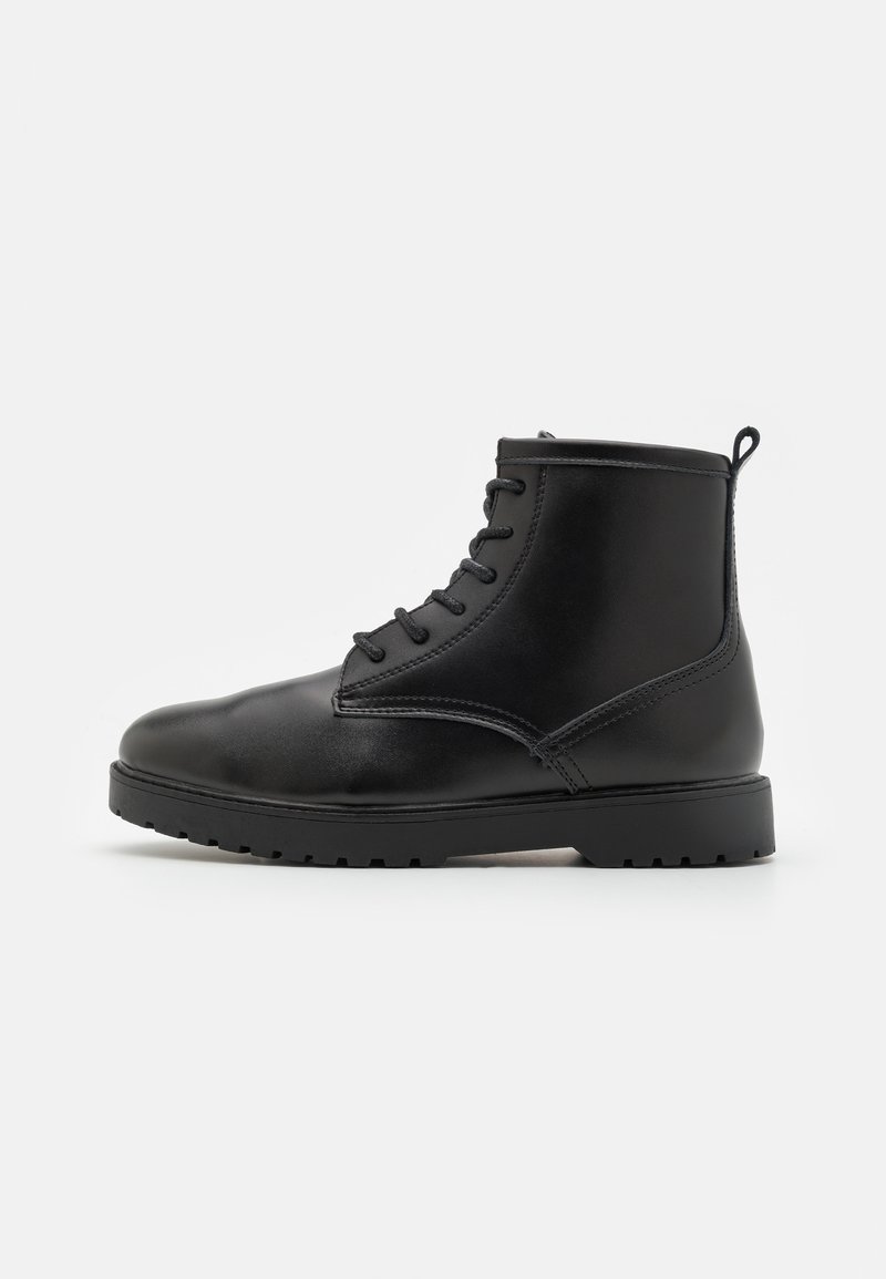 Černá kožená kotníková bota s kulatou špičkou, šněrovacím designem, texturovanou podrážkou a malým poutkem vzadu pro snadné obouvání.