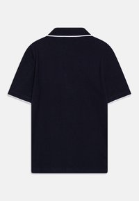 Polo shirt bleu marine avec un col, manches courtes, bordures blanches contrastantes le long du col et des manches, fabriqué en tissu en coton doux.