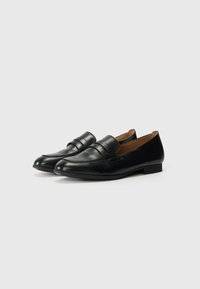 Sorte læder loafers med en glat overflade, rund tå og elastiske detaljer, der har en lav hæl og et minimalistisk design.
